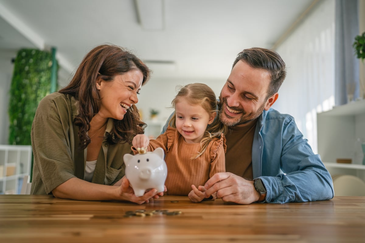 Familia colocando una moneda en una alcancía